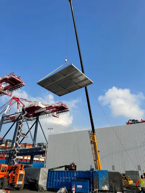 Crane lifting a fabricated curb cover onto a roof